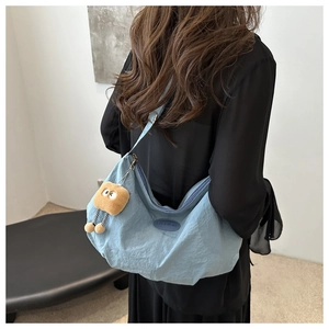 Detail of light blue crescent bag with fashion label and plush biscuit charm