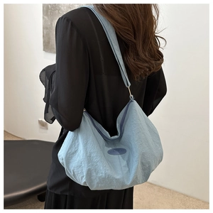Detail of light blue hobo bag with wrinkled texture and FASHION label on model
