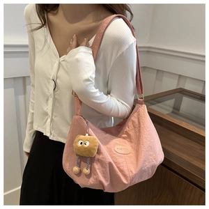 Detail of light pink pleated shoulder bag with FASHION label and plush charm accessory