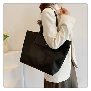 Detail view of large black commuter tote bag with white Fashion print and shoulder strap