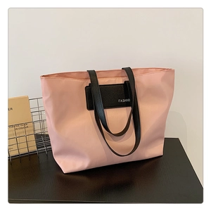 Detail of pink nylon tote bag featuring black leather patch and white FASHION logo