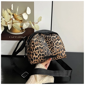Detail of leopard print shell bag featuring a black zipper and adjustable nylon strap
