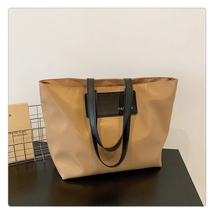 Detail of solid nylon tote bag with black shoulder strap and Fashion label patch
