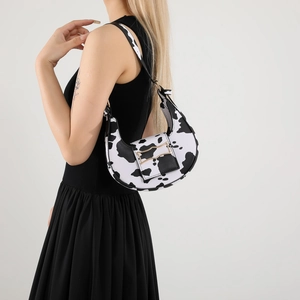Fashionable half-moon underarm bag with black and white cow print and metal hardware