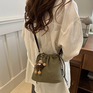 Army green large capacity drawstring bucket bag with plush charm on a shoulder strap
