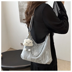 Detalle de bolso plateado plisado con colgante de nube de felpa blanca y cadena de metal
