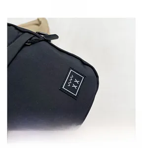 Detail of black fabric crossbody bag featuring metal zipper and rectangular logo patch