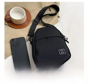 Detailed close-up of a mini black nylon crossbody bag featuring a square logo patch