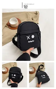 Detail of black canvas crossbody bag with white funny face print and zipper pockets