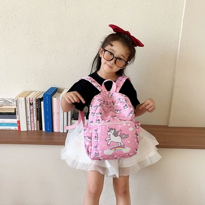 Pink school backpack for girls with cartoon unicorn and castle prints on kids shoulders