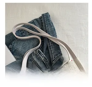 Close-up of white corduroy tote bag featuring red strawberry patterns and leather handles