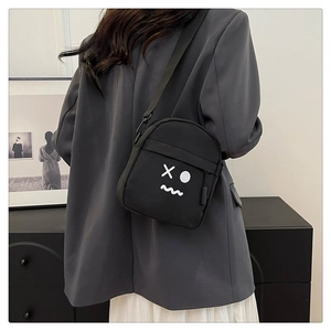 Detailed back view of a minimalist black canvas crossbody bag with cartoon face print