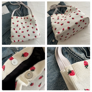 Detail view of corduroy strawberry tote featuring silver magnetic snaps and black lining
