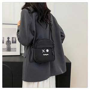 Detail of minimalist black crossbody chest bag with cartoon graphic on a model