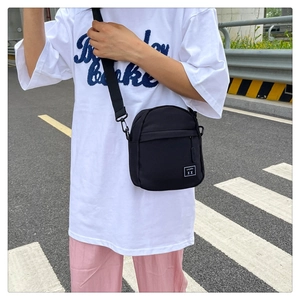 Detail of durable black nylon crossbody bag with adjustable strap and designer label