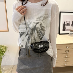Klassische schwarze Mini-Satteltasche mit Steppmuster und Kettenriemen an einem Model