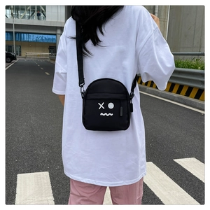 Close-up of black nylon chest bag featuring minimalist cartoon face print and adjustable strap