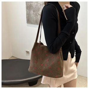 Detail shot of brown corduroy tote bag with red strawberry pattern and shoulder strap