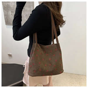 Close-up of brown corduroy tote bag with strawberry embroidery worn on shoulder