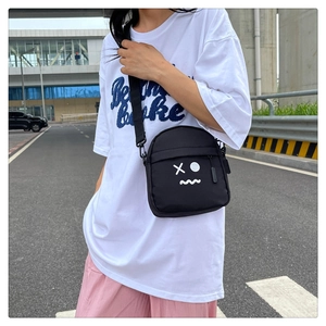Detailed street style view of a black crossbody chest bag with minimalist face graffiti