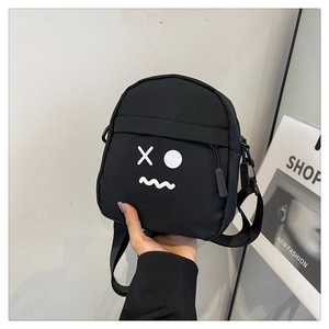 Detailed close-up of a black canvas crossbody bag featuring a white cartoon emoji print