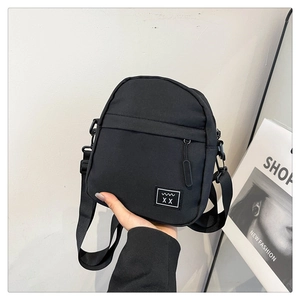 Detail of minimalist black nylon crossbody bag with adjustable strap and front zipper pocket