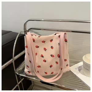 Close-up of pink corduroy tote bag with strawberry prints on a metallic shelf