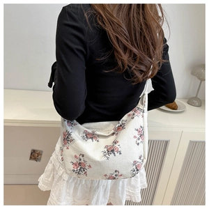 Detailed texture of beige corduroy crossbody bag with pink floral patterns on model