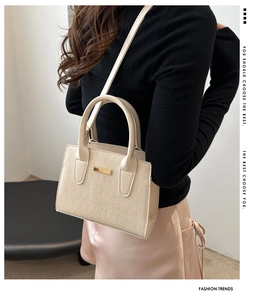 Detail of cream stone texture crossbody bag with gold hardware shown on model