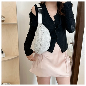 Detailed view of a light gray crescent waist bag with crinkled texture on a female model