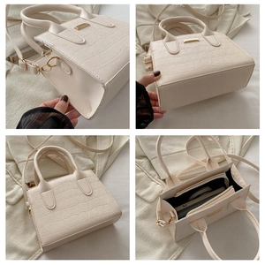 Detail showing crocodile-embossed cream handbag with gold hardware and spacious interior