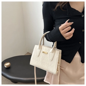 Detail of cream faux crocodile leather handbag with elegant gold metal buckle and handle