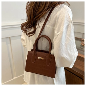 Brown crocodile pattern crossbody bag showing elegant side view on a model