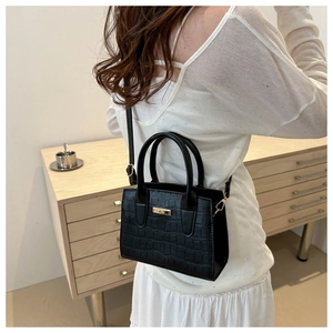 Detailed shot of black crocodile embossed handbag with golden hardware and shoulder strap