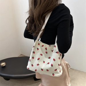 Japanese style white corduroy bucket bag with strawberry print shown on model shoulder