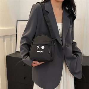 Minimalist black canvas crossbody chest bag featuring a white emoji face design for casual wear