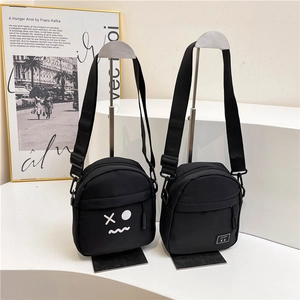 Minimalist black nylon crossbody bag with street style graffiti print and adjustable strap