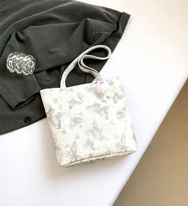 Detail van witte tote bag met vlinderprint en zachte pluche bal hanger voor dames