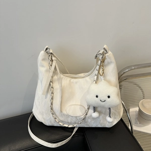 Bolso de hombro blanco minimalista con cadena plateada y colgante de nube en un banco