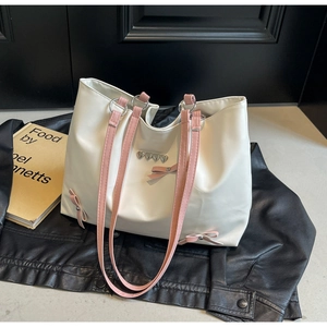 Macro view of cream tote bag featuring pink ribbons and metal heart decorations
