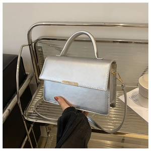 Détail du sac à main argenté métallisé avec poignée ronde et garniture en métal chic