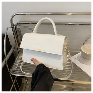 Détail du sac à main blanc carré avec fermoir métallique doré et texture cuir lisse