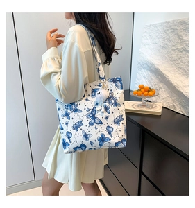 Detail van witte shopper met blauwe vlinderpatronen en witte pluche hanger