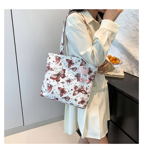 Detailopname van een witte vlinder tote bag met roze pluizige bol en laarshangers