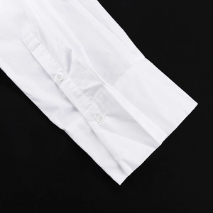 Détail macro des poignets d'une chemise en coton blanc avec boutons doubles et coutures fines