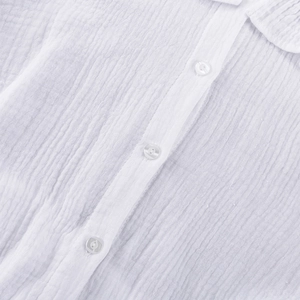 Détail de chemisier blanc en coton avec texture crépon et boutons ronds blancs