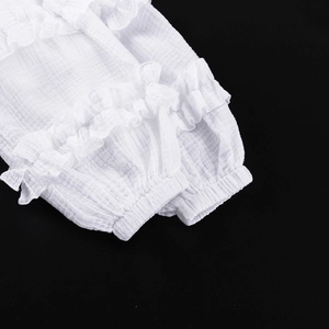 Détail de la manche d'une chemise en mousseline de coton blanc avec bords à volants et poignets
