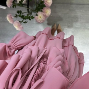 Detail of pink ruffled dress showing layered pleats and delicate fabric texture