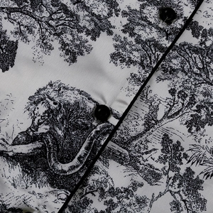 Detalle de tela Toile de Jouy con botones negros y motivo de león en la camisa
