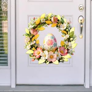 Close-up of Easter wreath with pink flowers, gold leaves and painted egg decoration